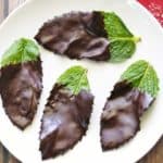 Chocolate mint leaves are served on a white plate with a napkin.