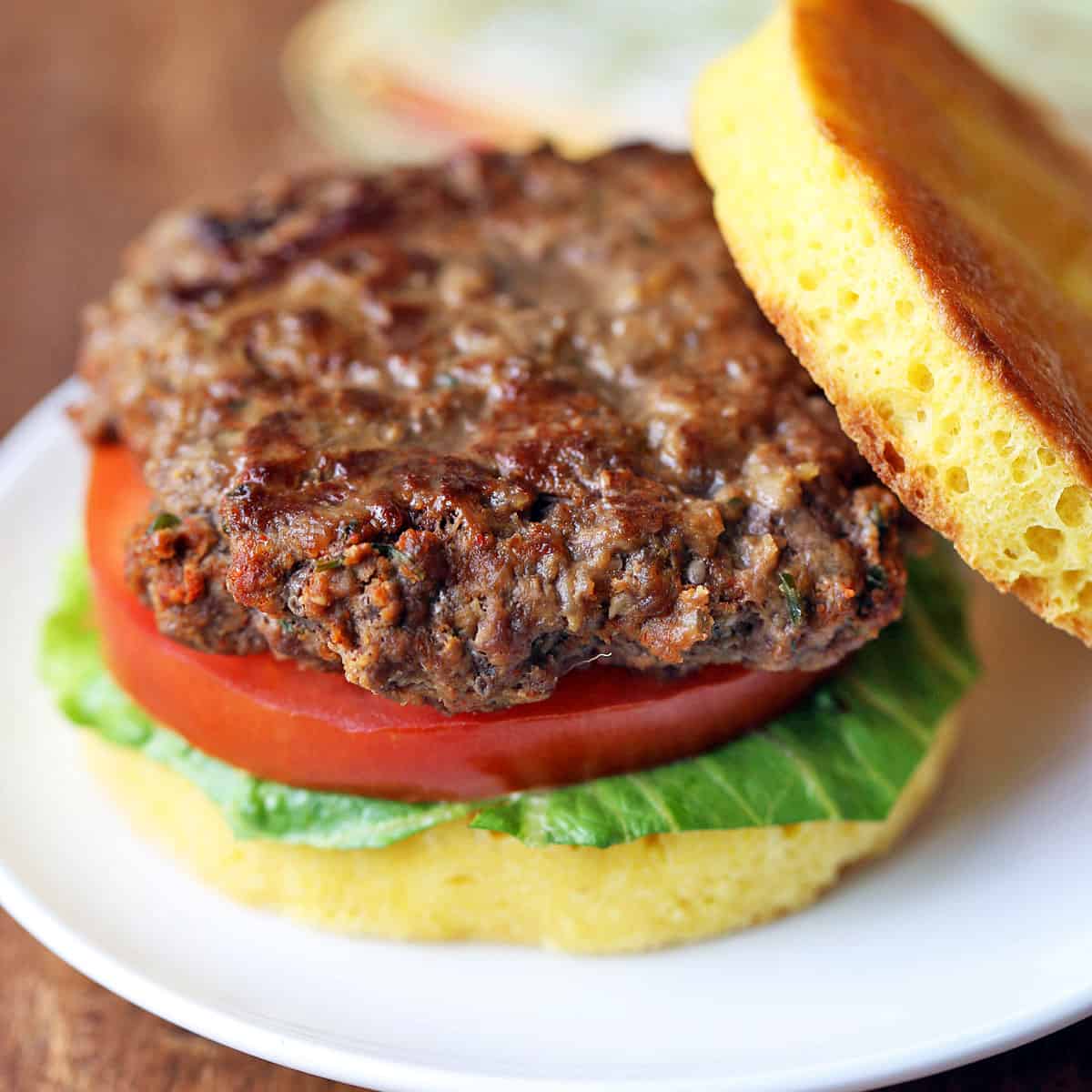 Bison burger is served in a bun with lettuce and tomato.