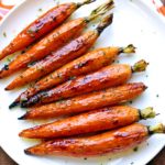 Roasted carrots are served on a white plate.