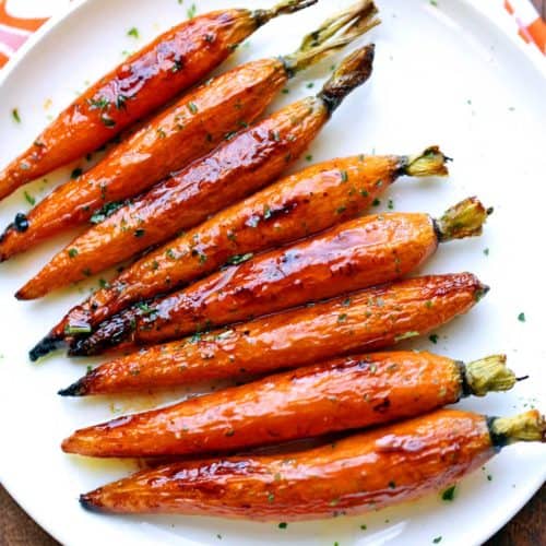 Roasted carrots are served on a white plate.