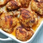 Baked boneless skinless chicken thighs in a white baking dish.