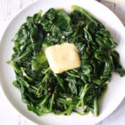 Sauteed spinach is topped with butter.