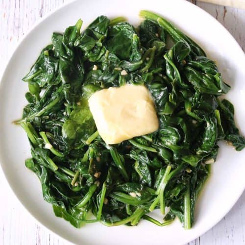 Sauteed spinach is topped with butter.