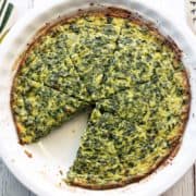 Crustless spinach quiche is served in a white pie plate.
