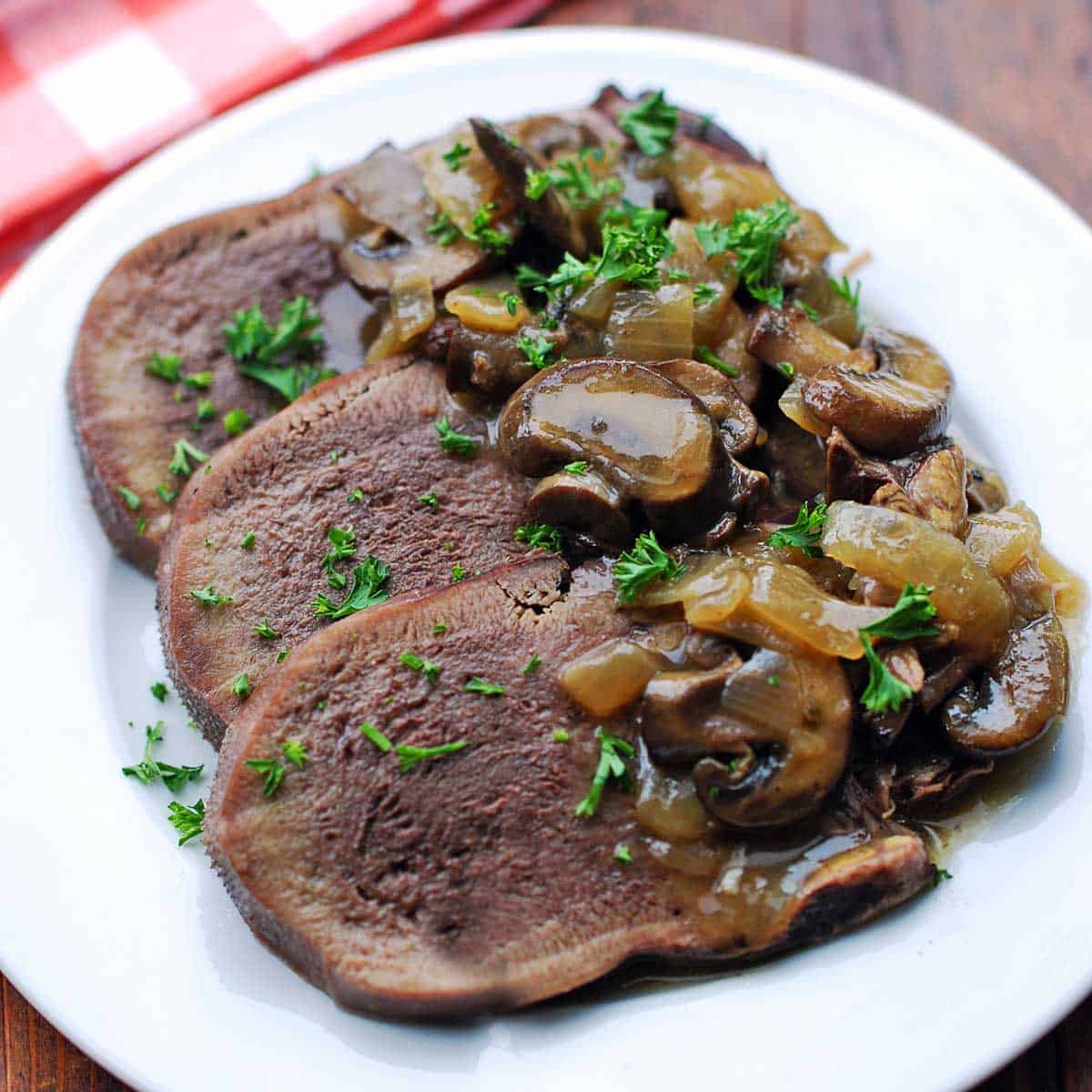 Beef tongue slices are topped with onions and mushrooms.