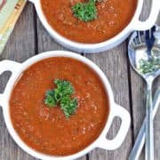 Gazpacho is served in white bowls with spoons.