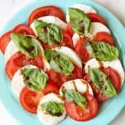 Caprese salad is served on a blue plate.