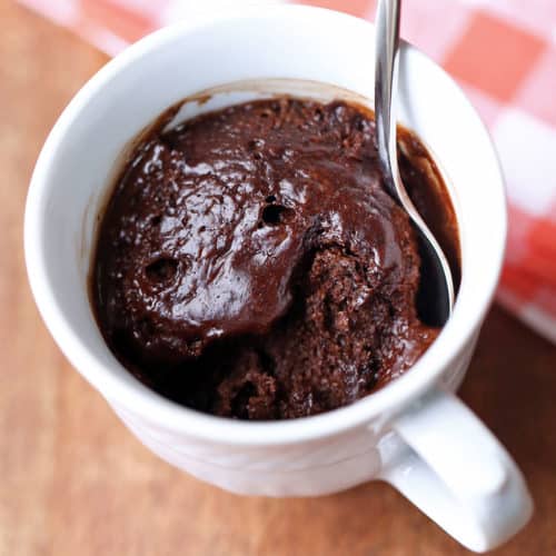 Keto chocolate mug cake is served in a white mug with a spoon.