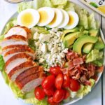 Chicken Cobb salad is served on a white plate.