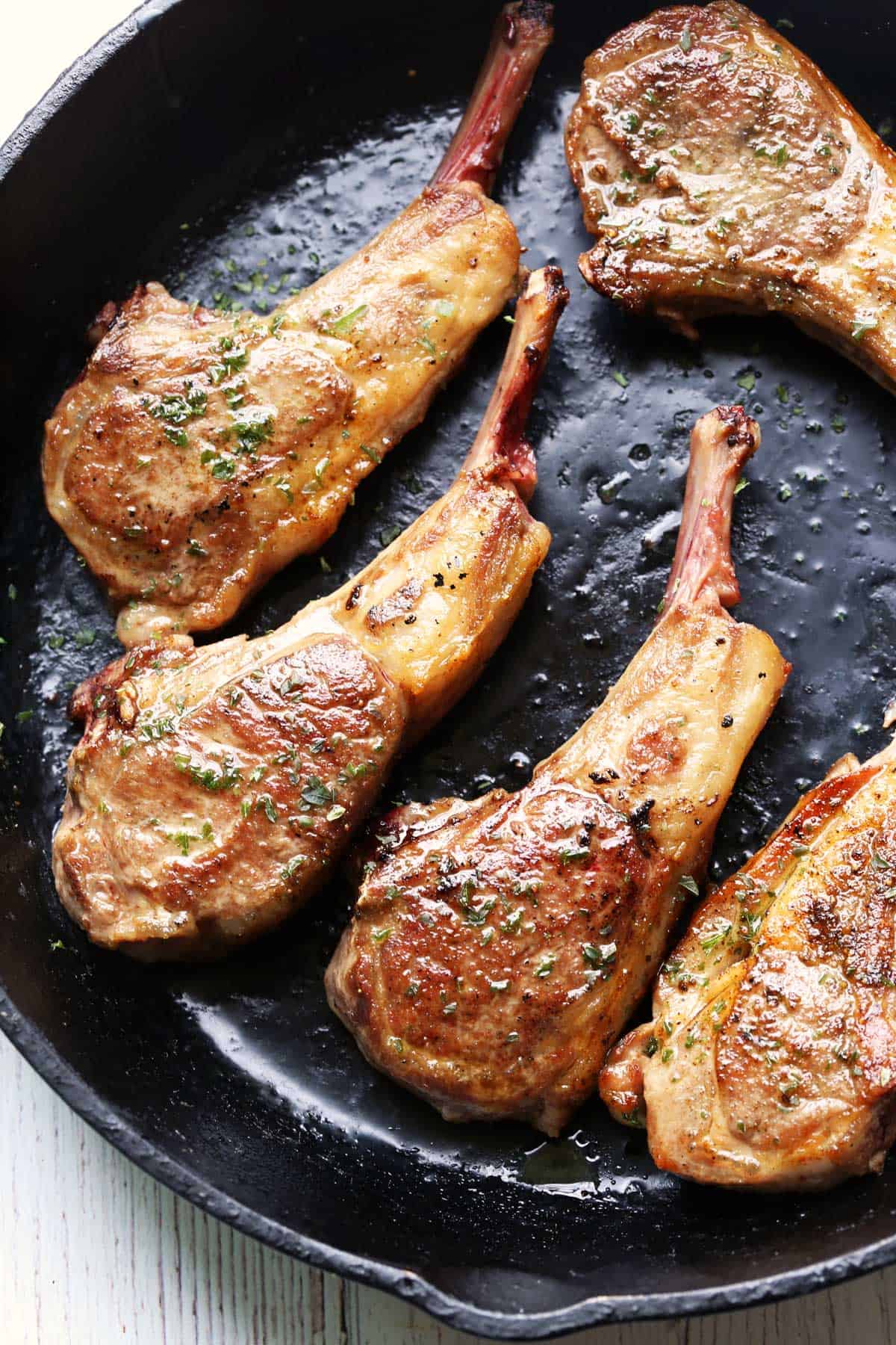 Pan-fried lamb chops in a cast-iron skillet.