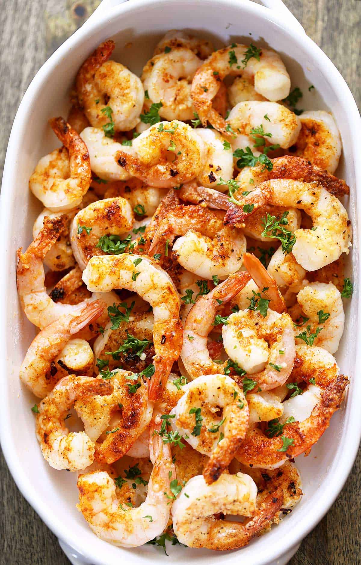 Baked shrimp are served in a white ceramic baking dish.
