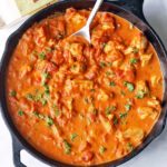 Keto butter chicken is served in a skillet with a spoon.