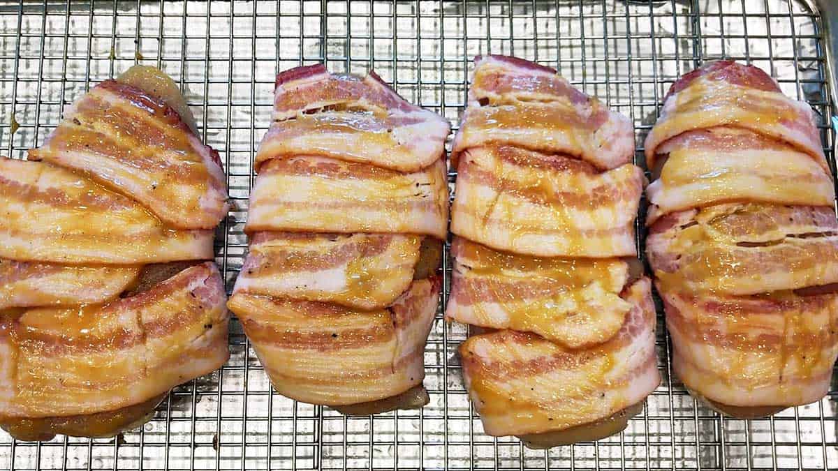Raw chicken breasts wrapped in bacon and brushed with a Dijon-honey sauce.