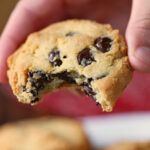 A hand is holding an almond flour chocolate chip cookie.