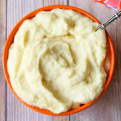 Mashed cauliflower is served in a bowl with a spoon.