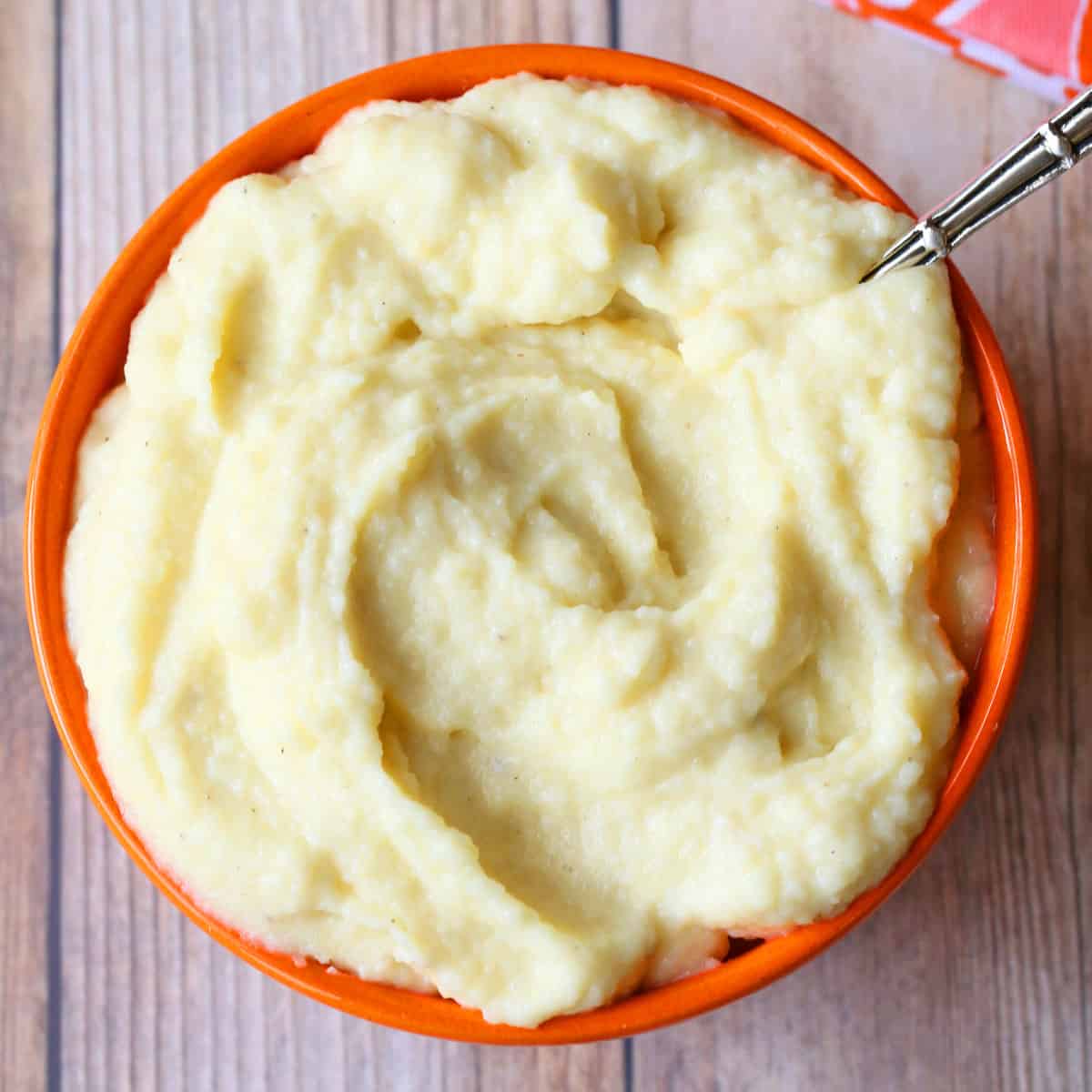 Mashed cauliflower is served in a bowl with a spoon.