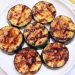 Grilled zucchini is served on a white plate.