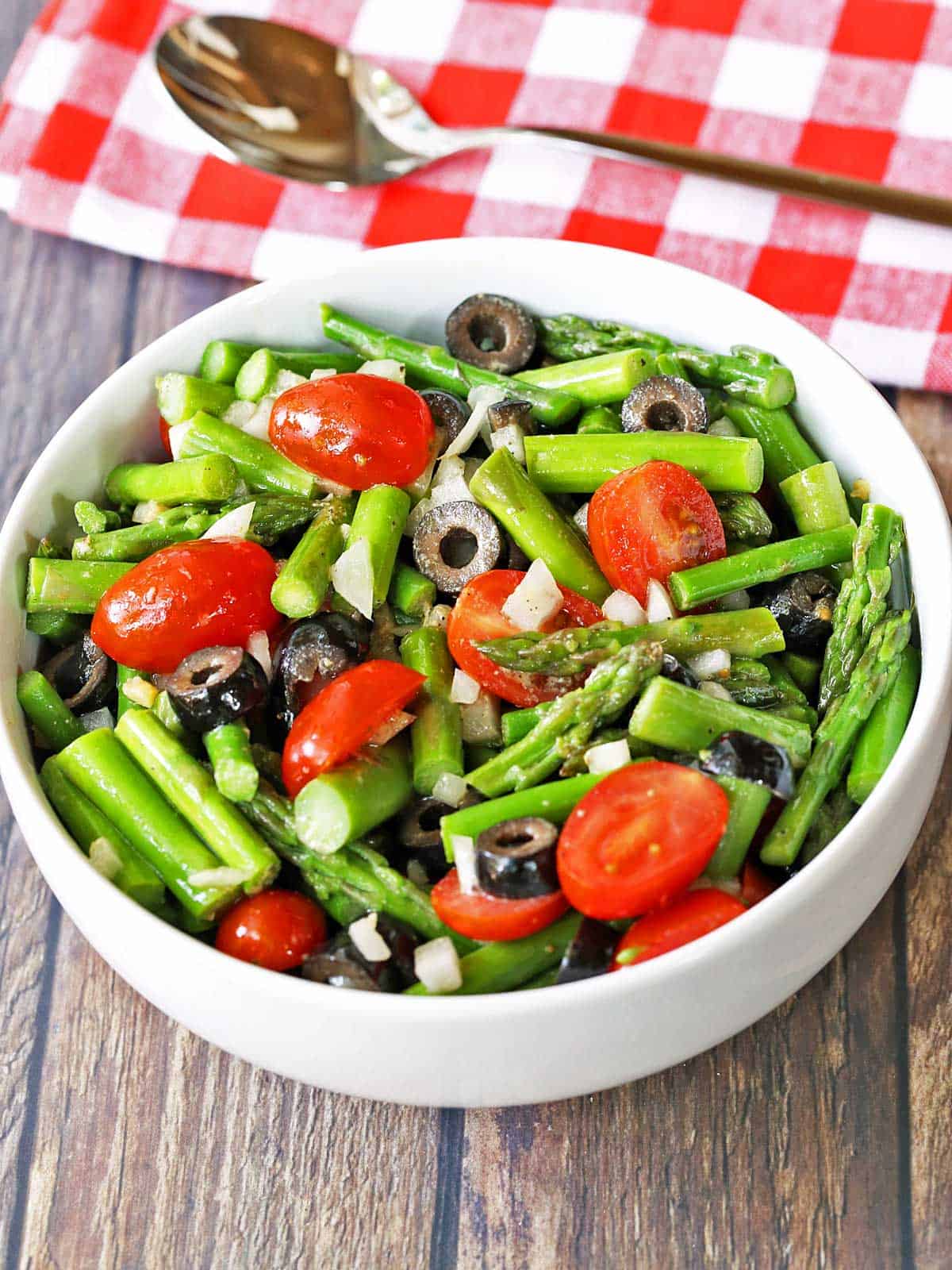 Asparagus salad is served in a white bowl. 