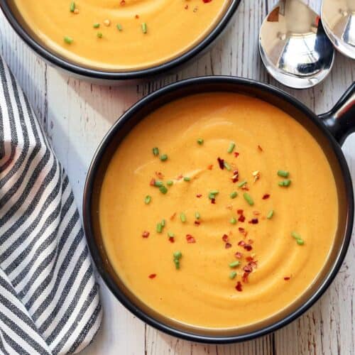 Butternut squash soup served in a dark bowl.