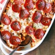 Keto pizza casserole is served in a white baking dish with a spoon.