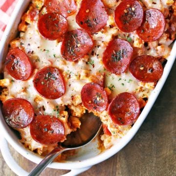 Keto pizza casserole is served in a white baking dish with a spoon.
