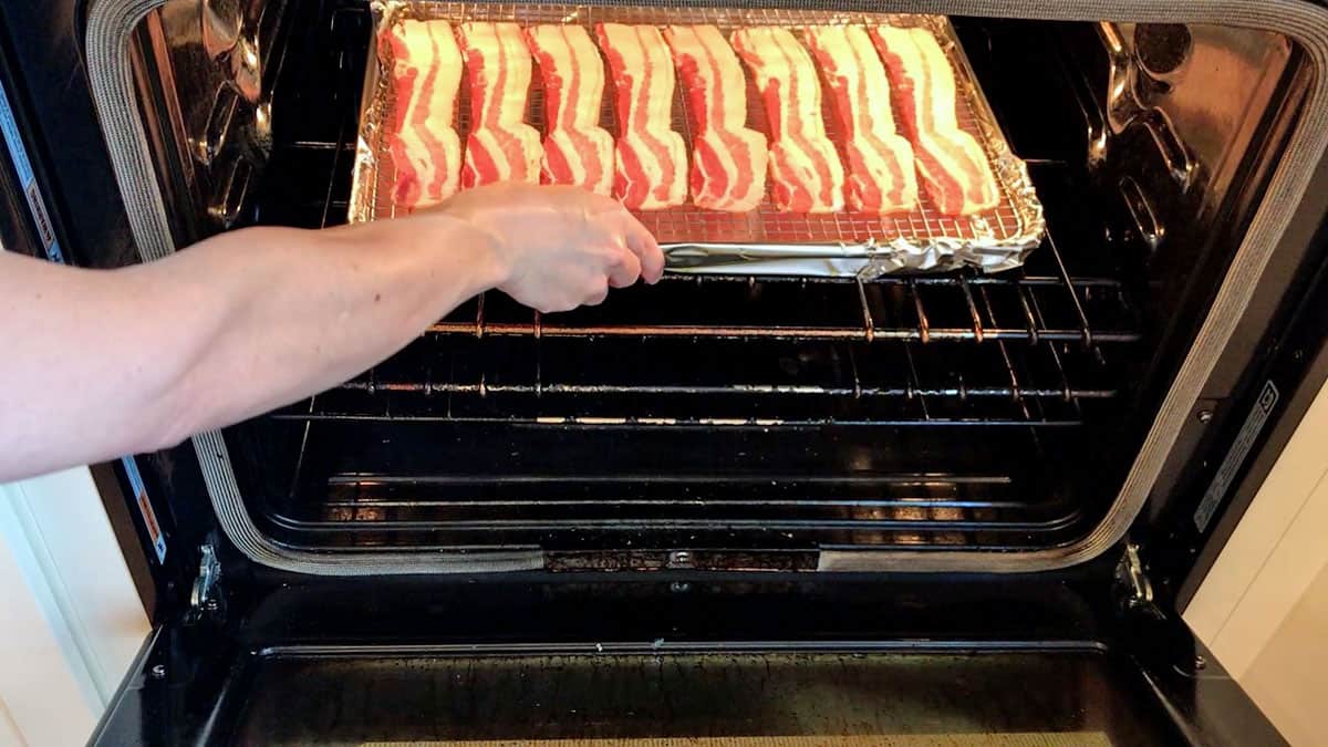 Putting a pan of bacon inside the oven.