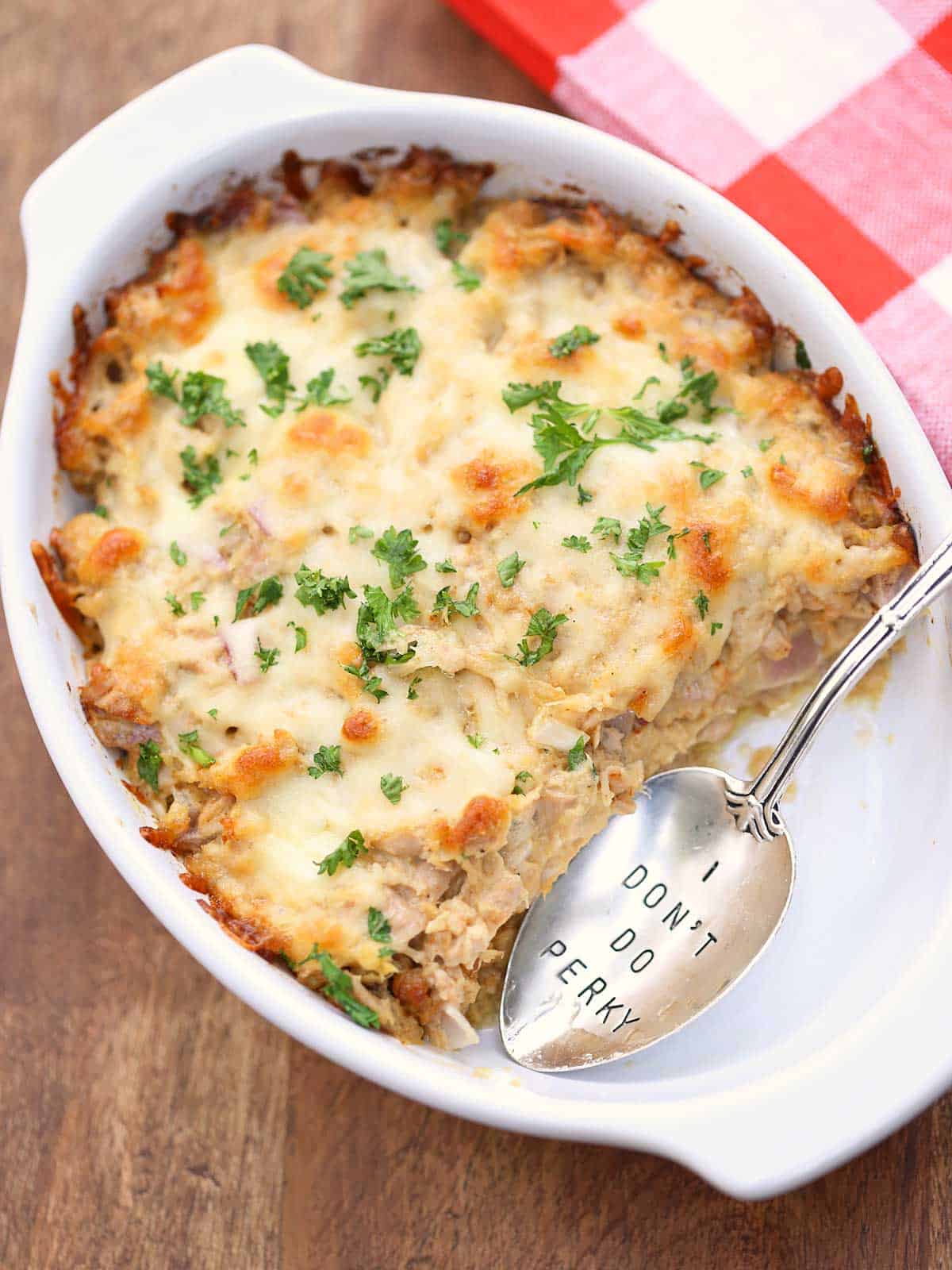 Keto tuna casserole is served in a white baking dish with a spoon.