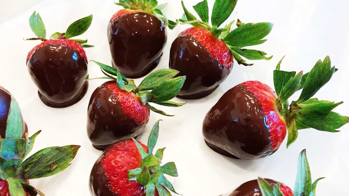 Chocolate-dipped strawberries arranged on a wax paper-lined plate.