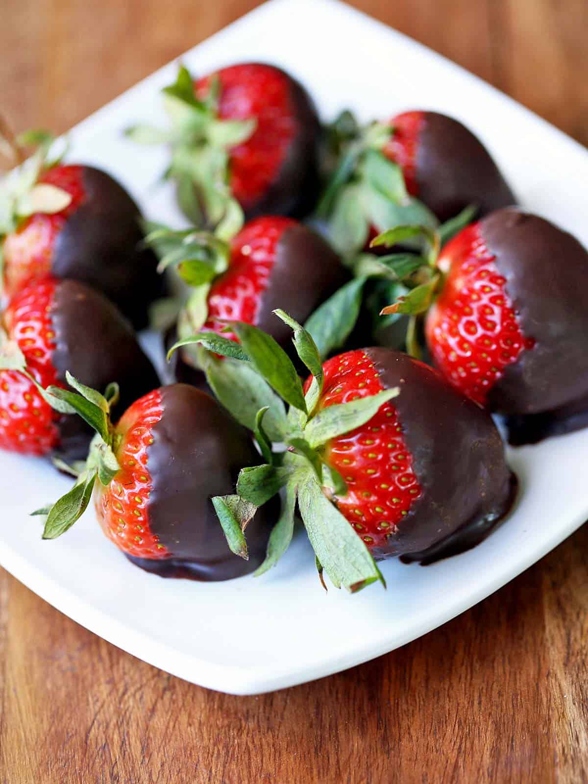 Chocolate covered strawberries are served on a white plate. 