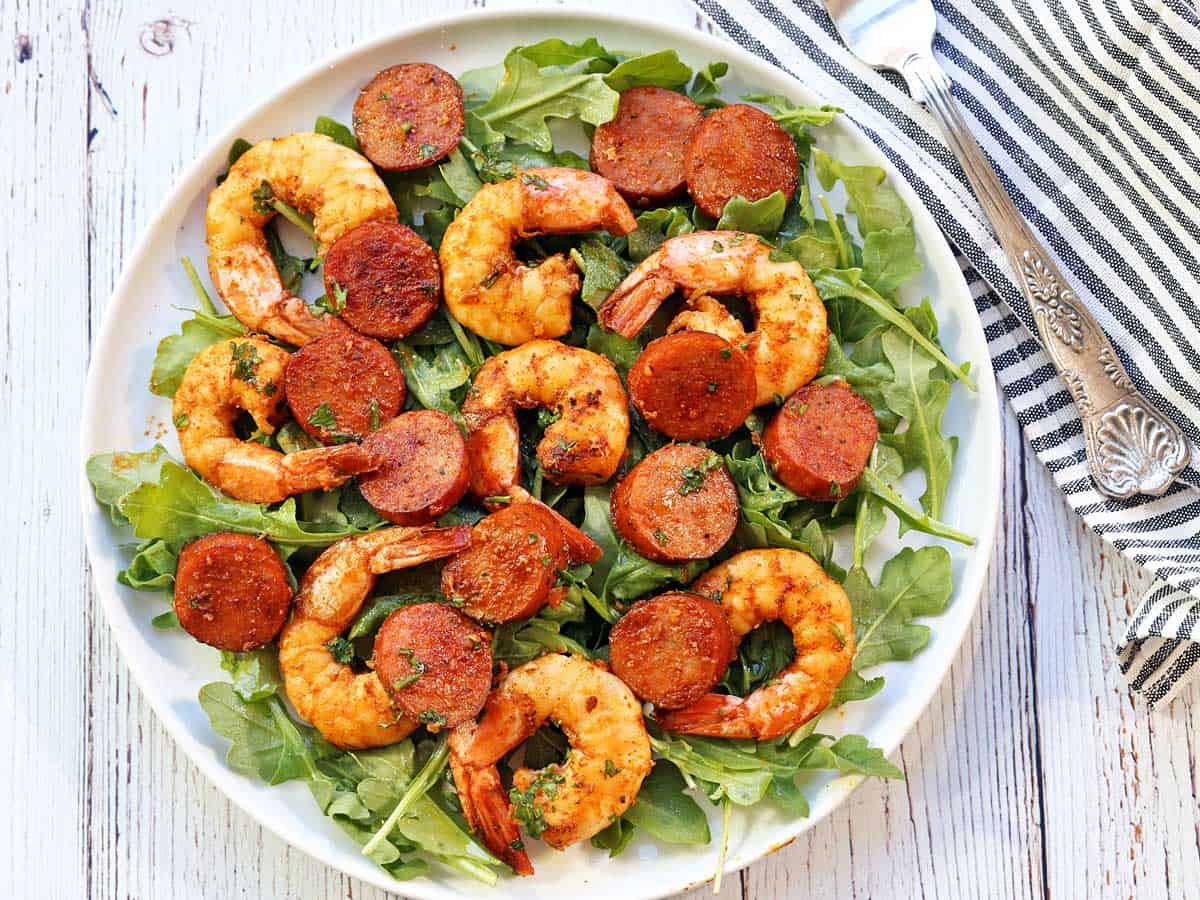 Shrimp and sausage served on a bed of arugula.