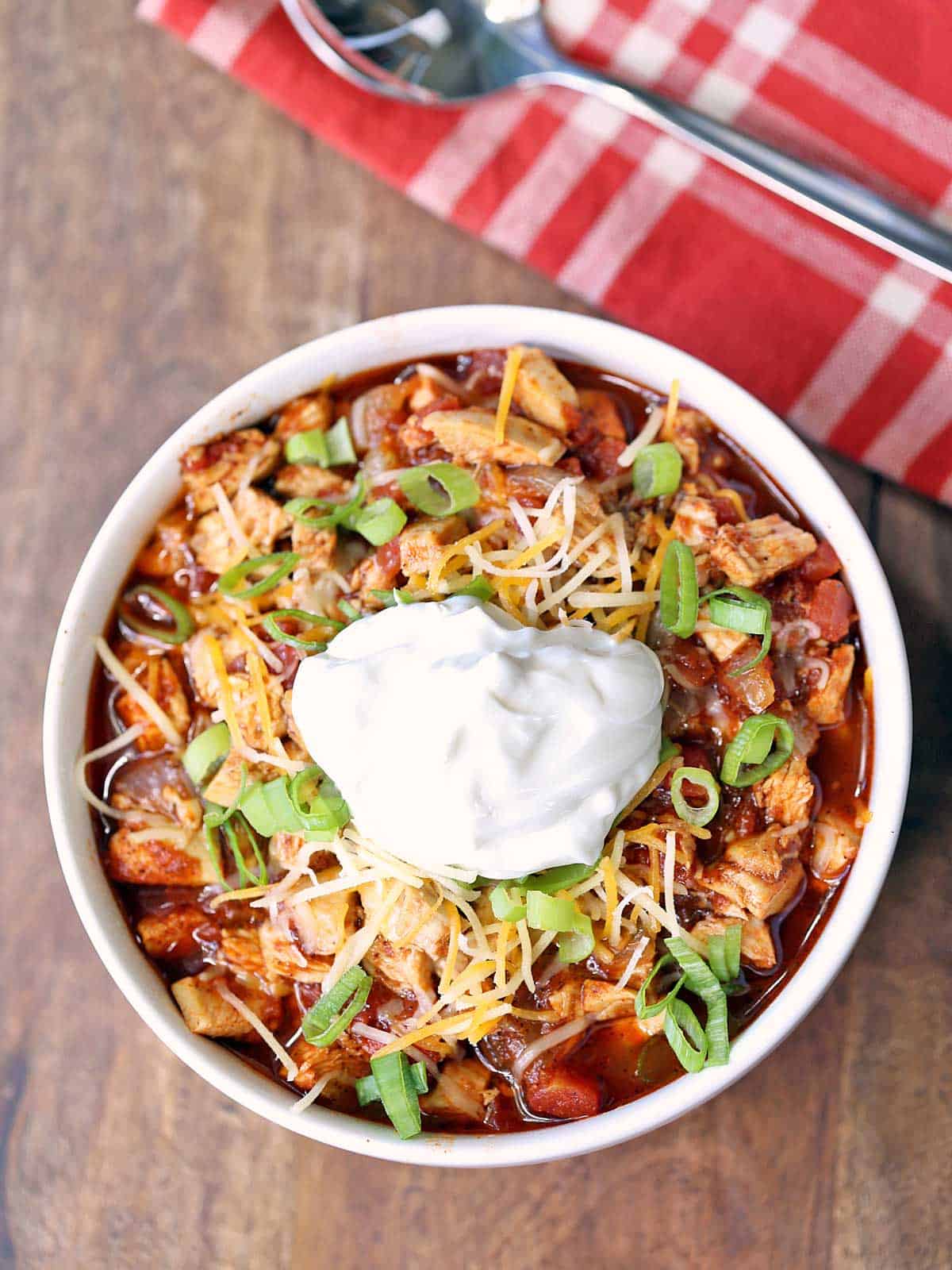 Leftover turkey chili is served in a bowl, topped with a dollop of sour cream. 