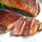 Duck breast, sliced, is served on a white plate.