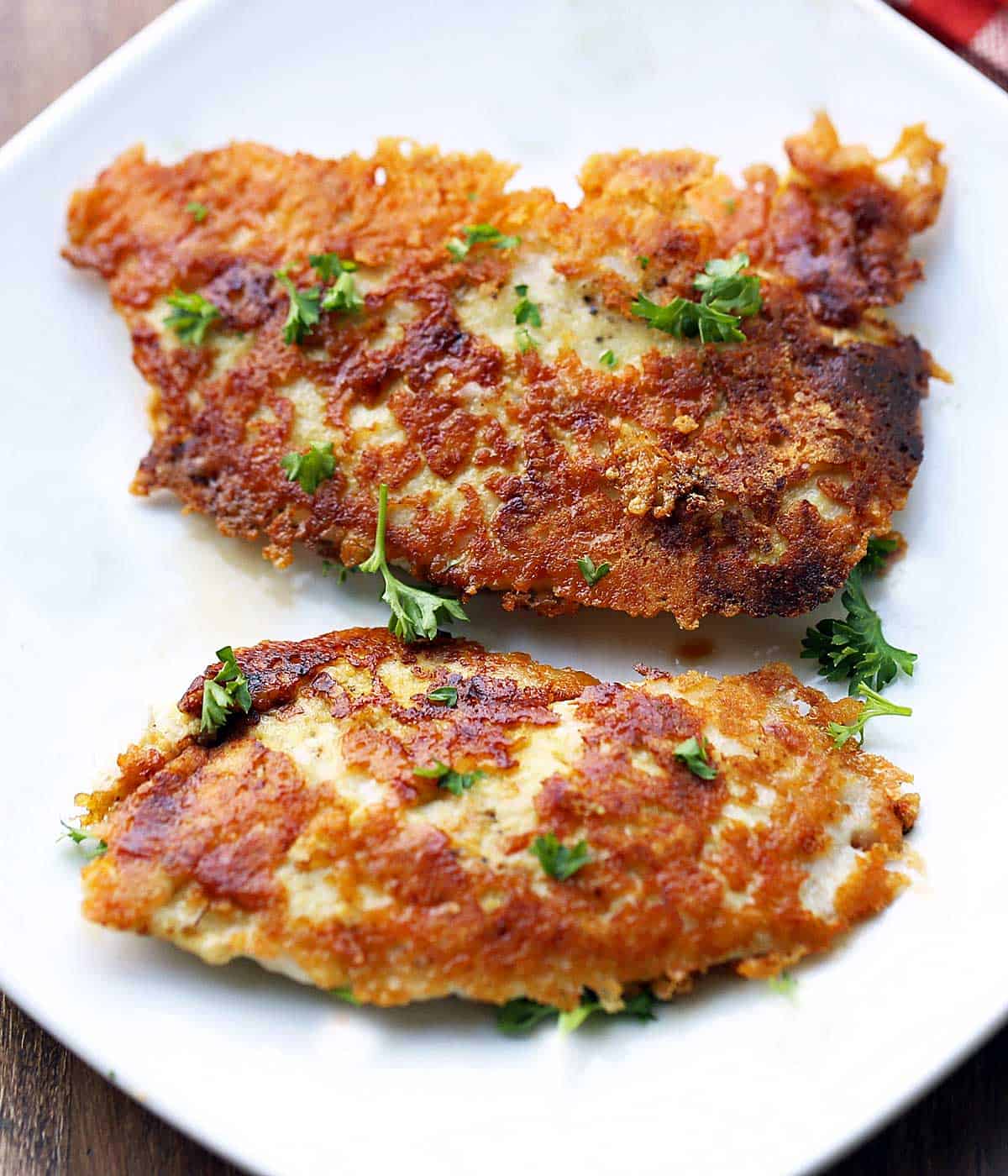 Keto parmesan chicken tenders are served on a white plate. 
