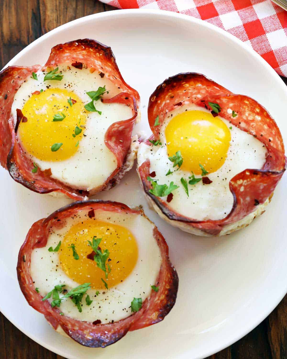 Salami and egg cups are served on a white plate. 