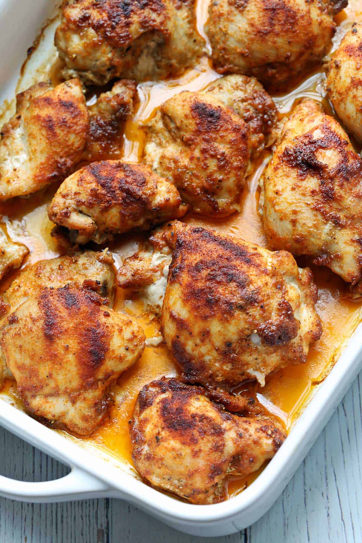 Boneless skinless chicken thighs are served in a white baking dish.