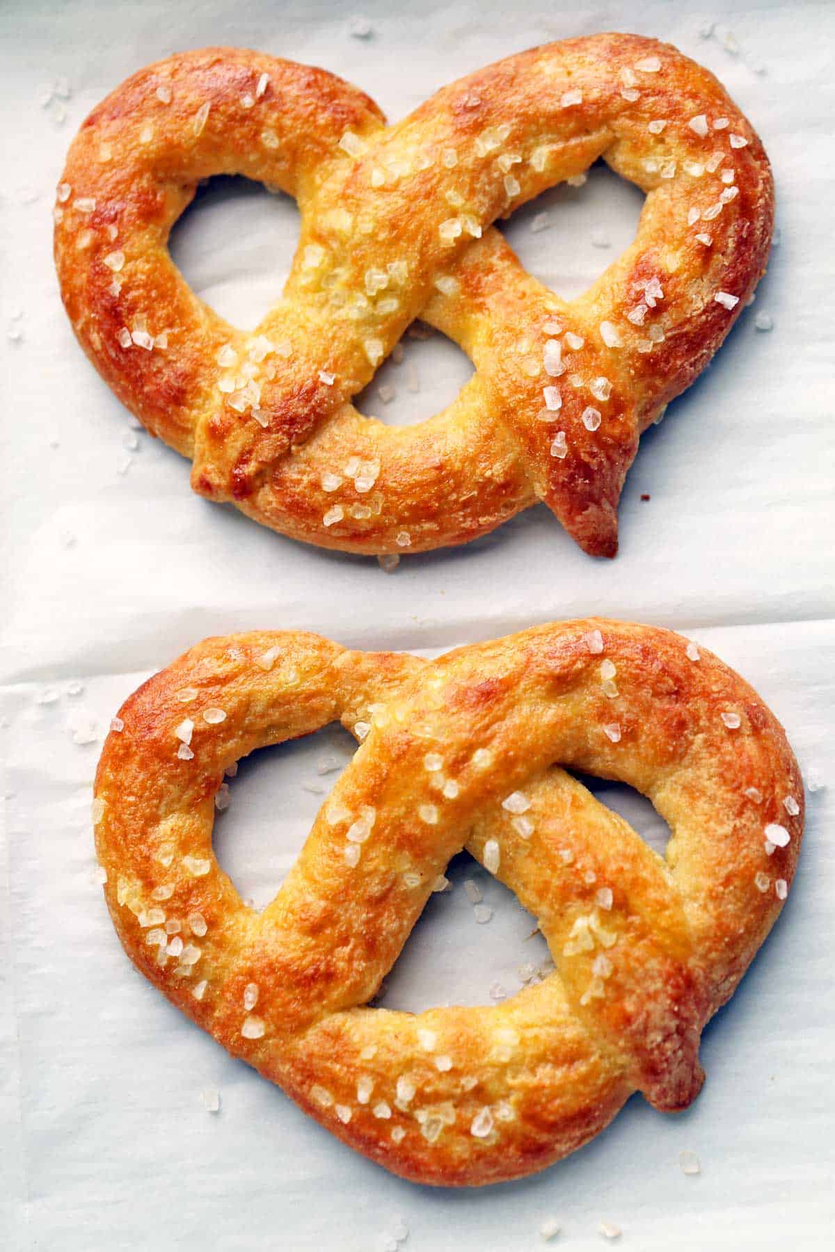 Two keto pretzels on a parchment-lined baking sheet.