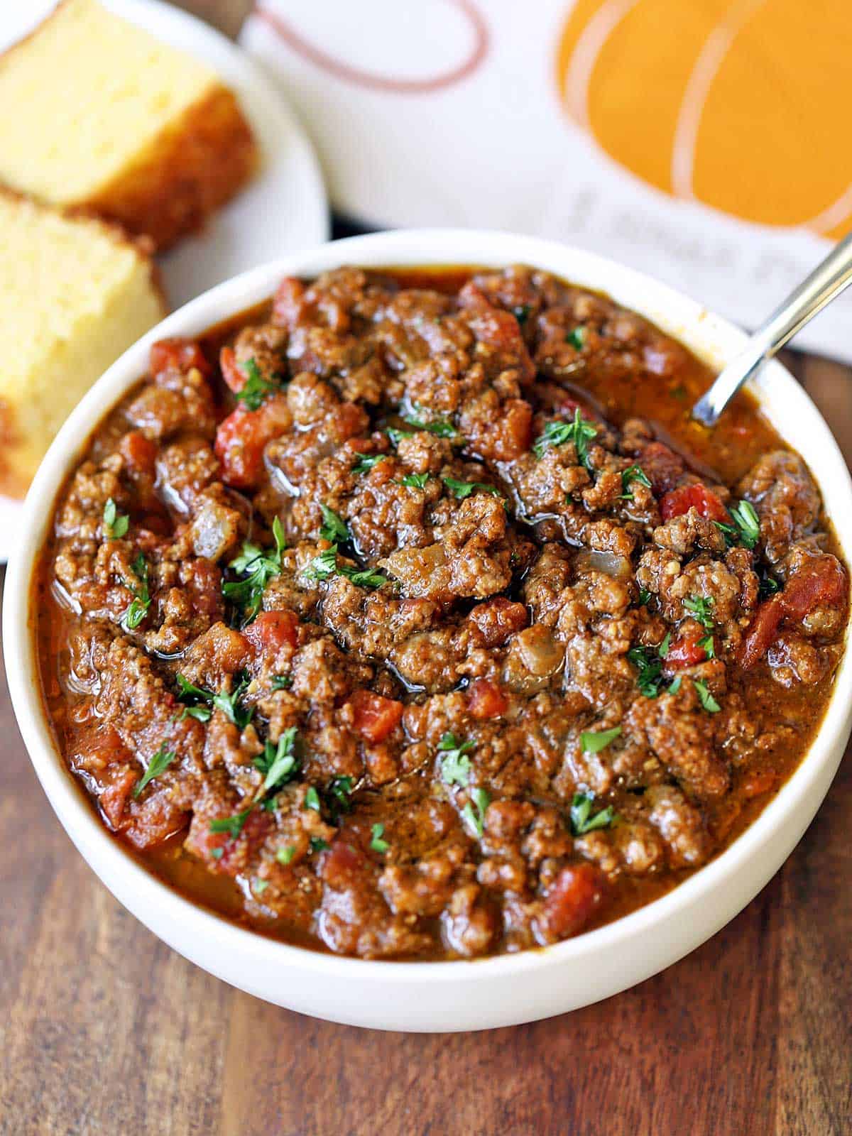Pumpkin chili is served with a spoon and cornbread. 