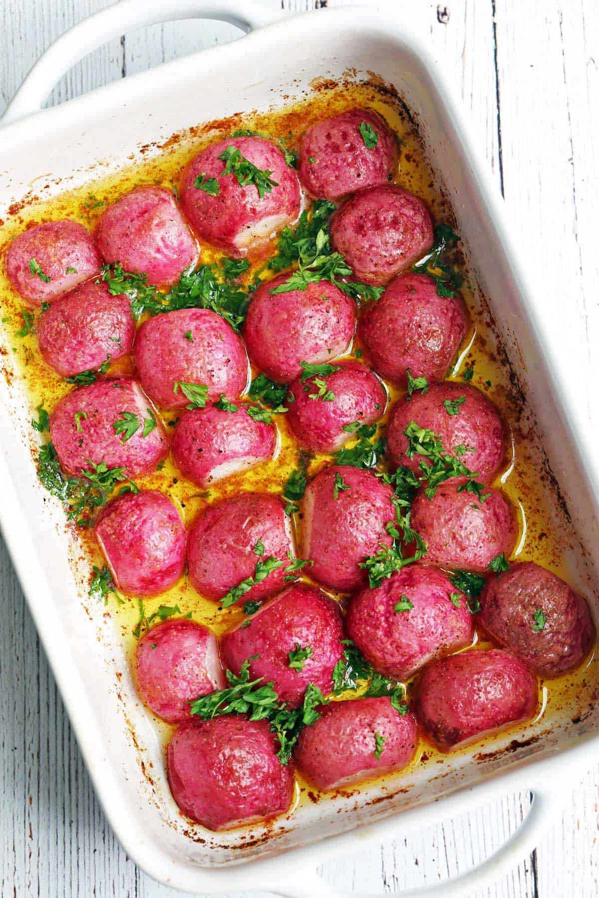 Roasted radishes are served in a white baking dish.