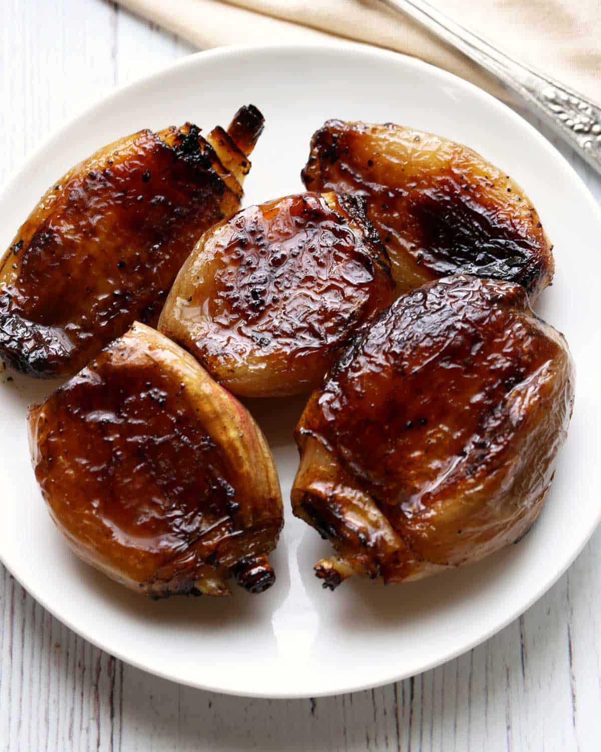 Caramelized shallots are served on a white plate.