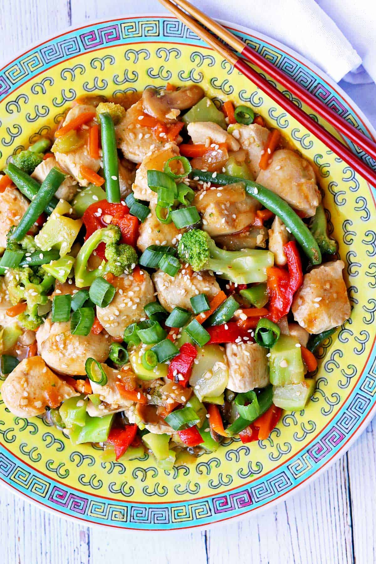 Chicken stir fry is served with chopsticks.