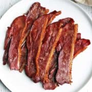 Duck bacon is served on a white plate.