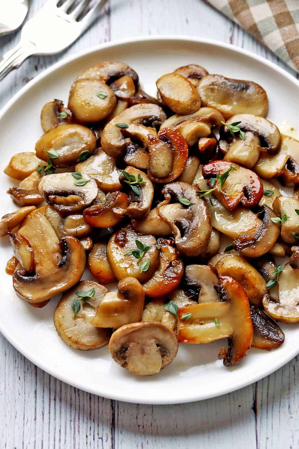 Sauteed mushrooms are served on a white plate.