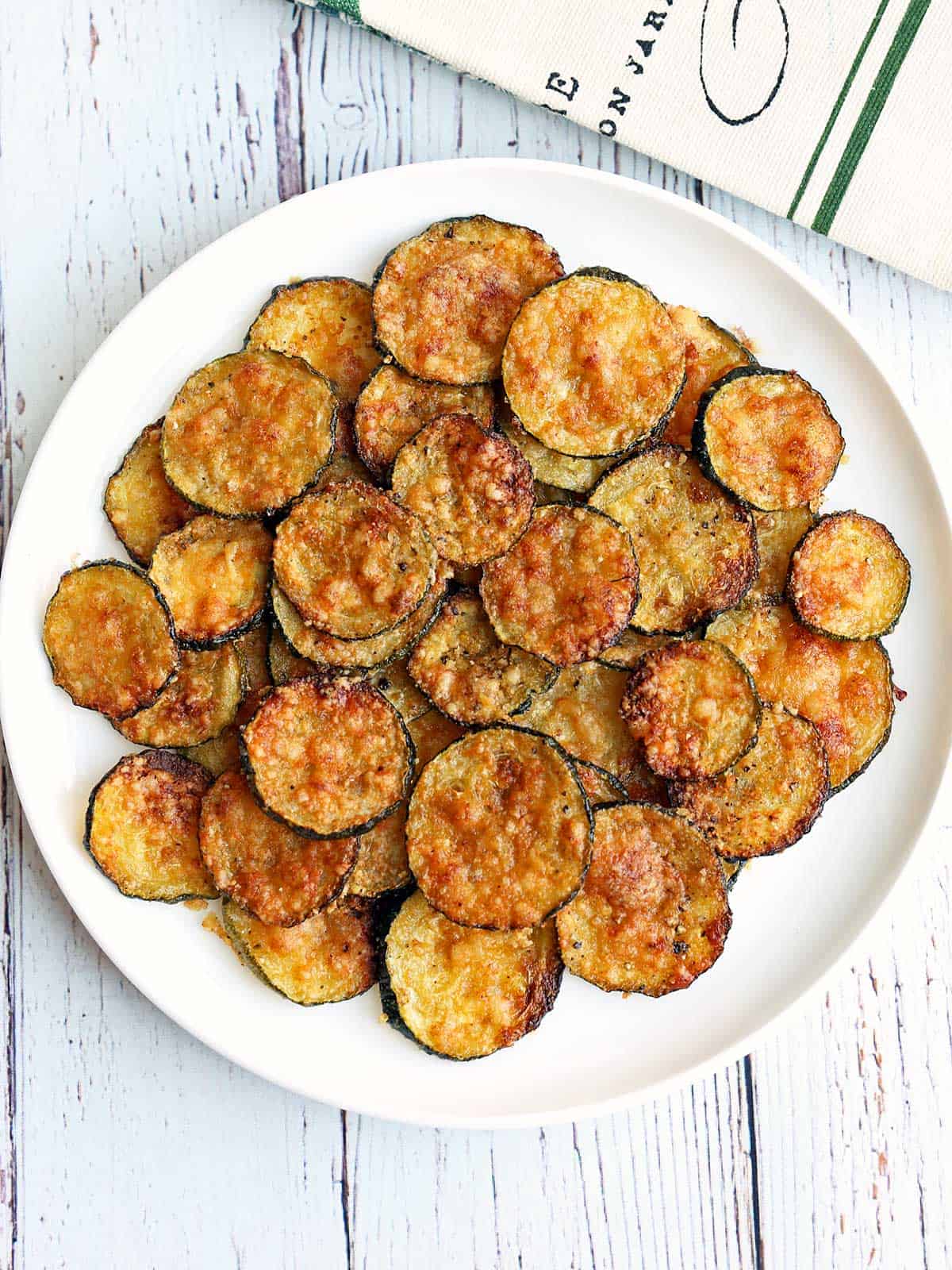 Zucchini chips are served on a white plate.