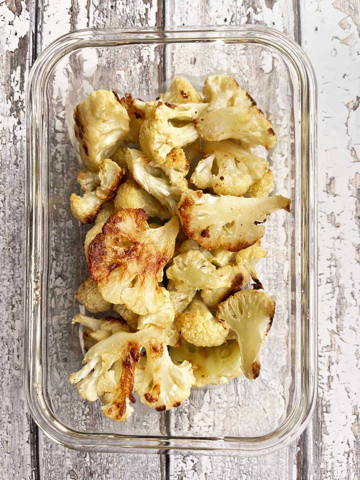 Roasted cauliflower leftovers are stored in a glass dish.