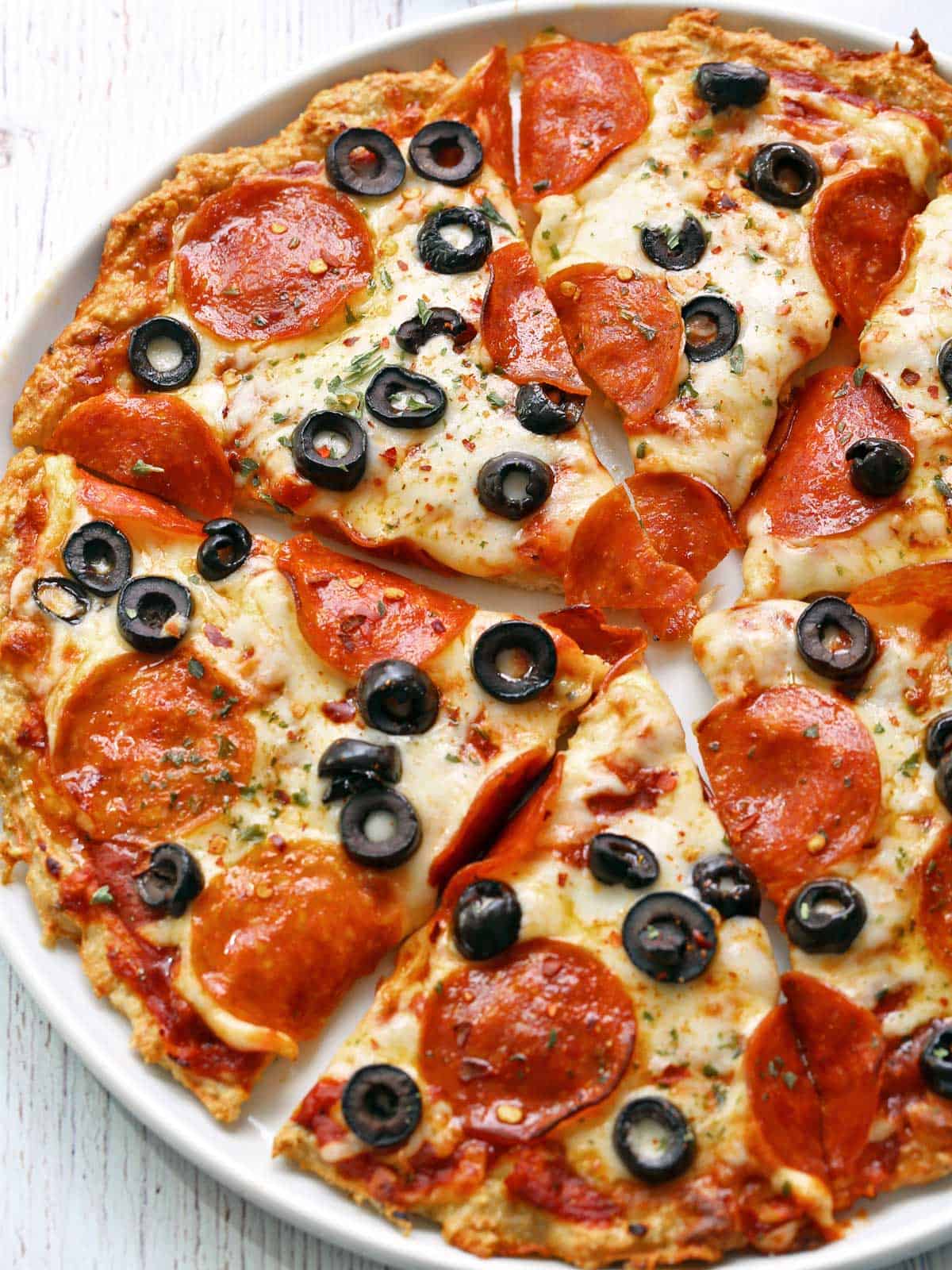 Chicken crust pizza is served on a white plate.