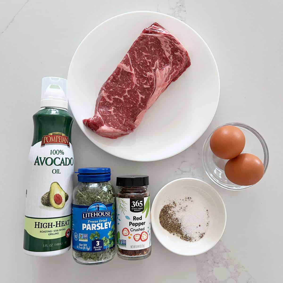 The ingredients needed to make a steak and eggs breakfast.
