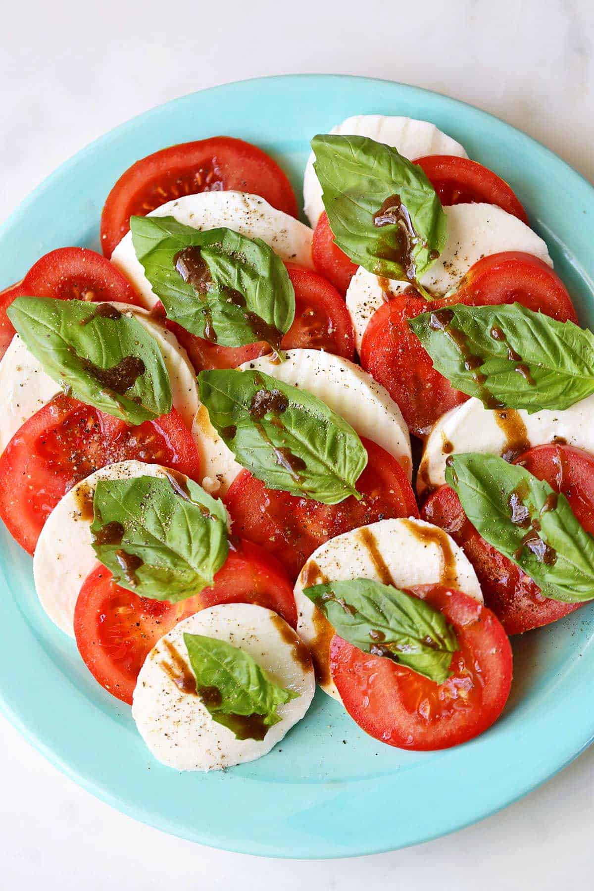 Caprese salad is served on a light blue plate.