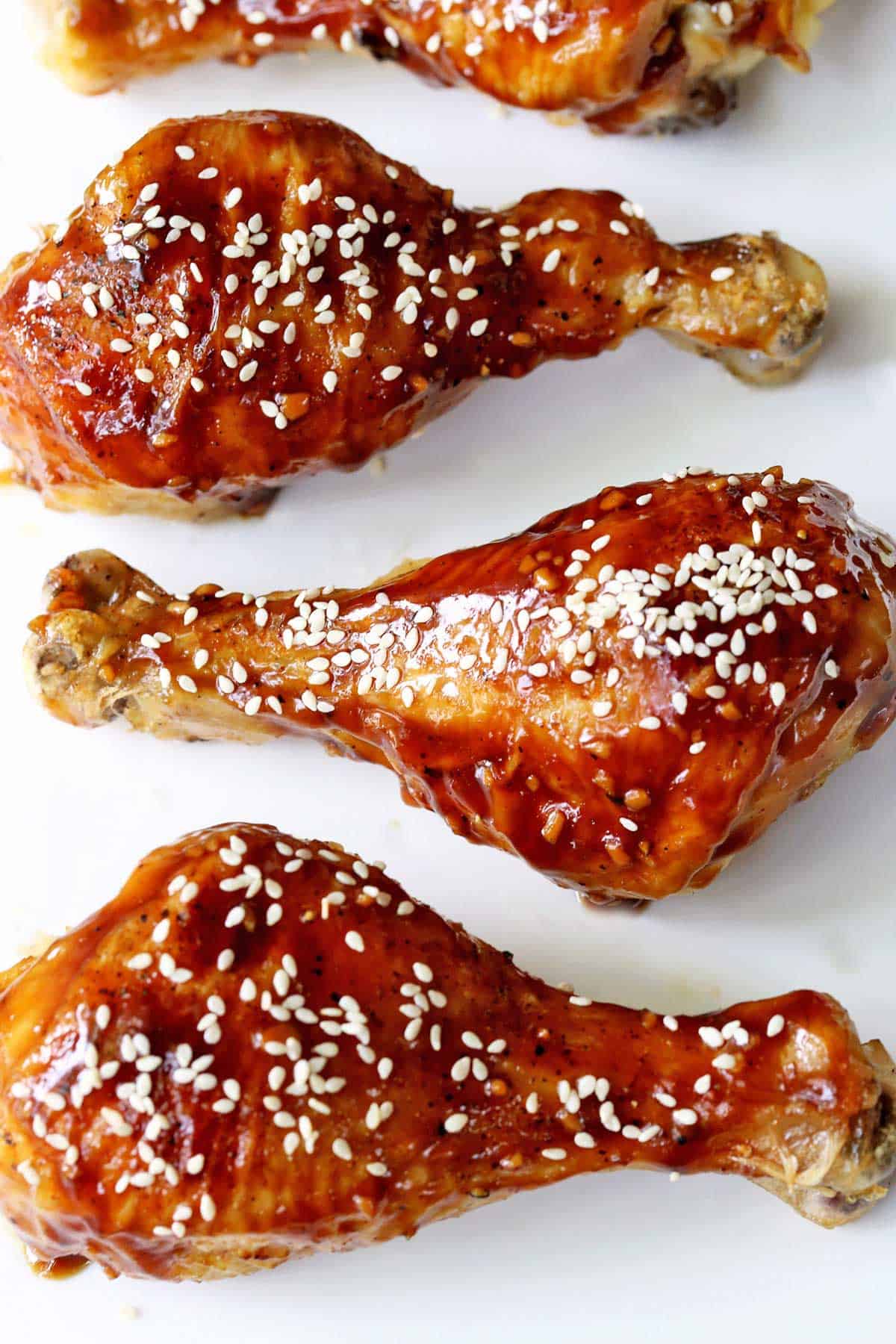 Teriyaki chicken drumsticks are served on a white plate. 