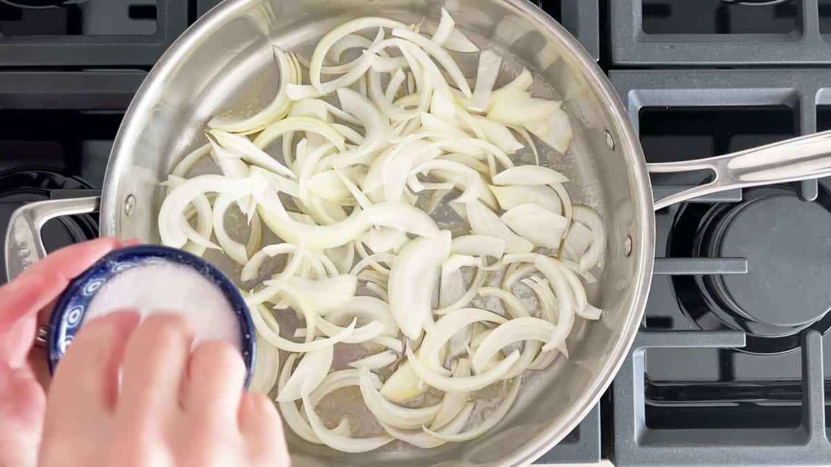 Sprinkling the onions in the skillet with salt.