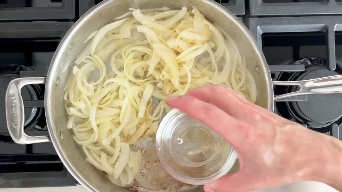 Adding water to the pan to deglaze the bottom.